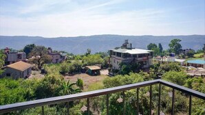 A residential area with houses surrounded by greenery and hills in the background. - FabHotel Chinar Residency (Jaoli)