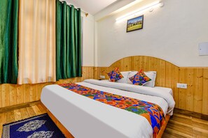 A room with a wooden headboard bed, a colorful geometric-patterned bedspread, and a blue patterned rug. - Fabhotel Suvidha Cottage (Manali)