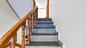 A staircase with wooden balusters and a handrail, leading to an upper floor. - Fabhotel Suvidha Cottage (Manali)