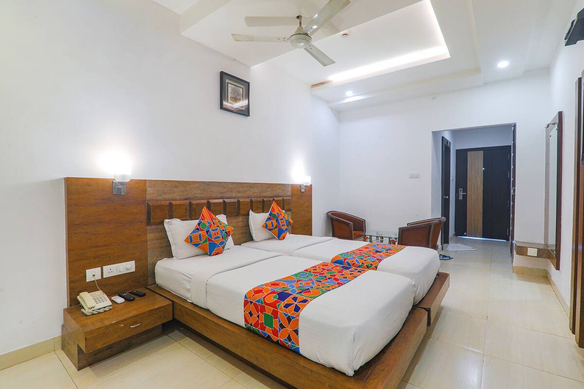 A hotel room with a large bed, bedside tables, a ceiling fan, and a door leading to another room.