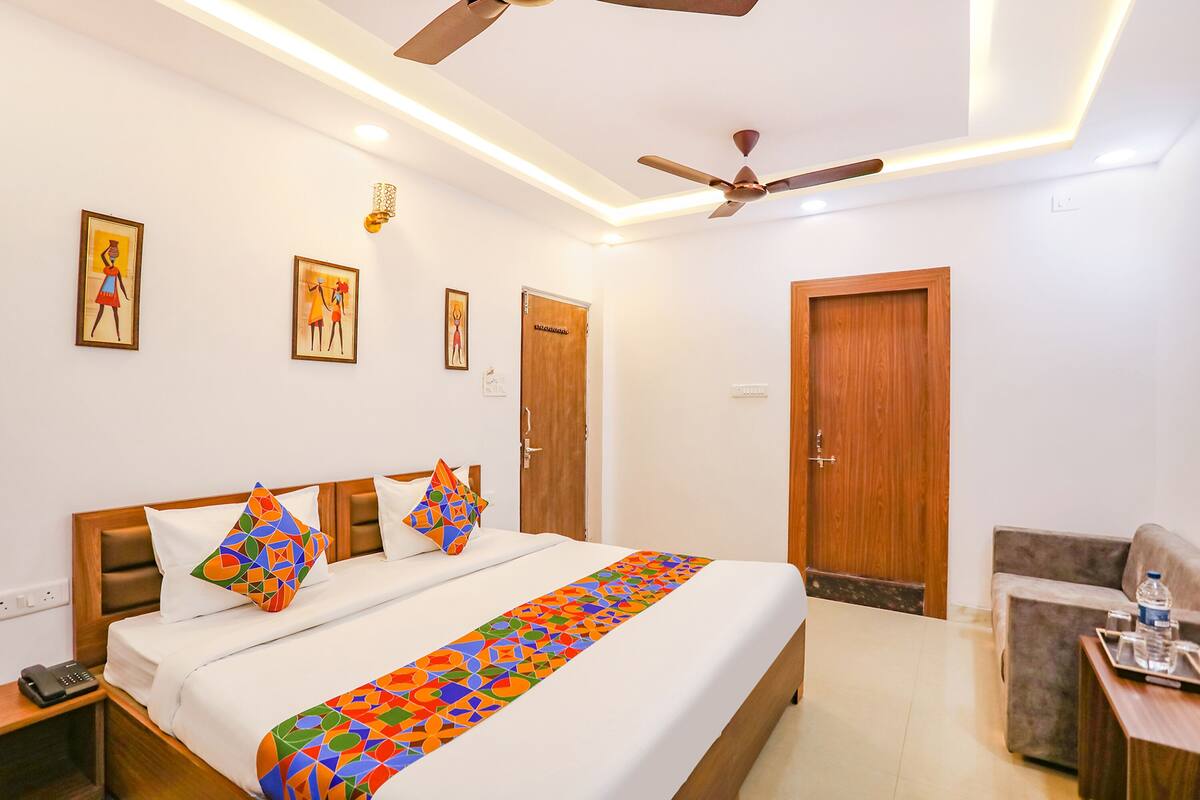 A hotel room with a large bed, a ceiling fan, and a sofa.
