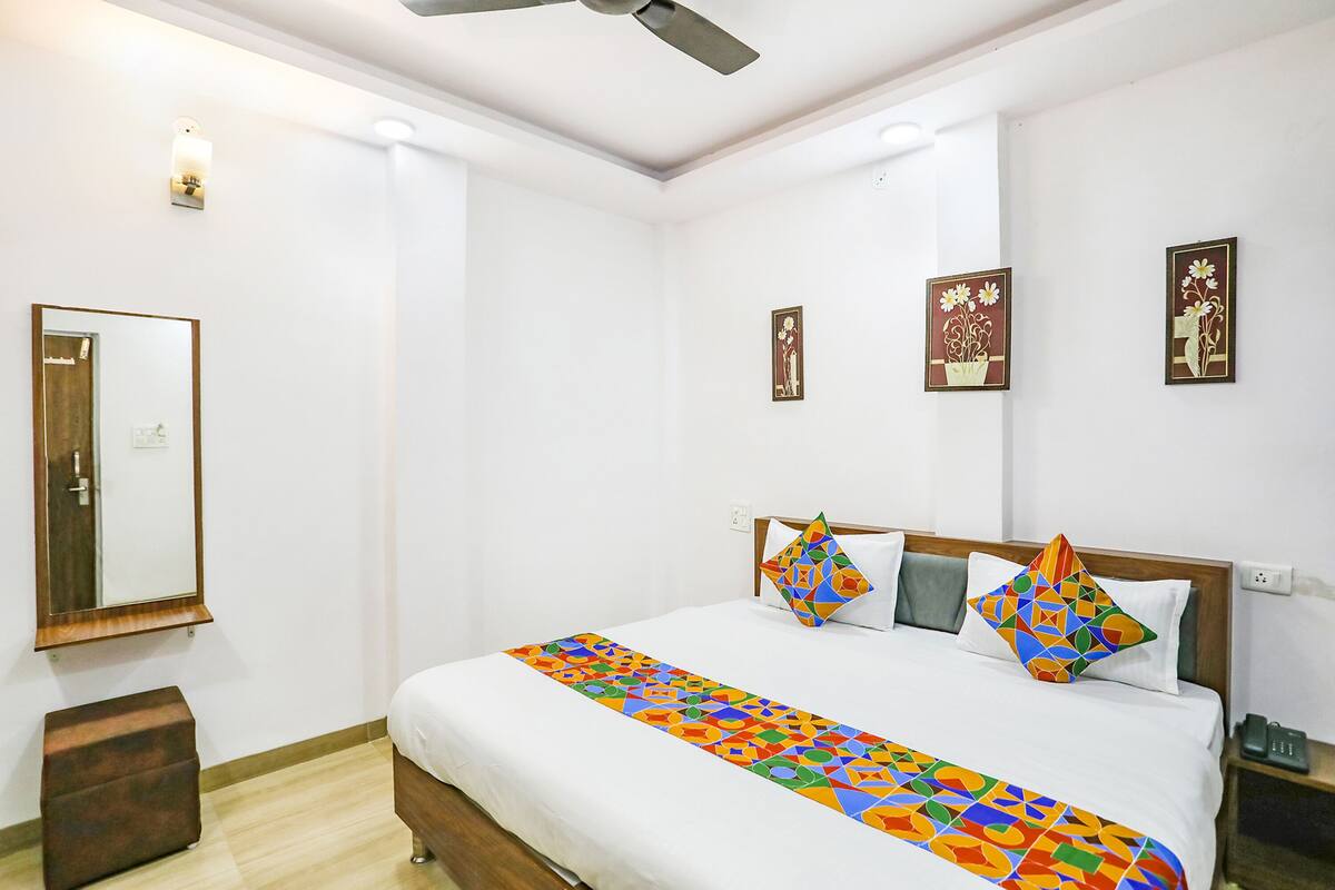 A hotel room with a bed, a nightstand, a mirror, and wall art.
