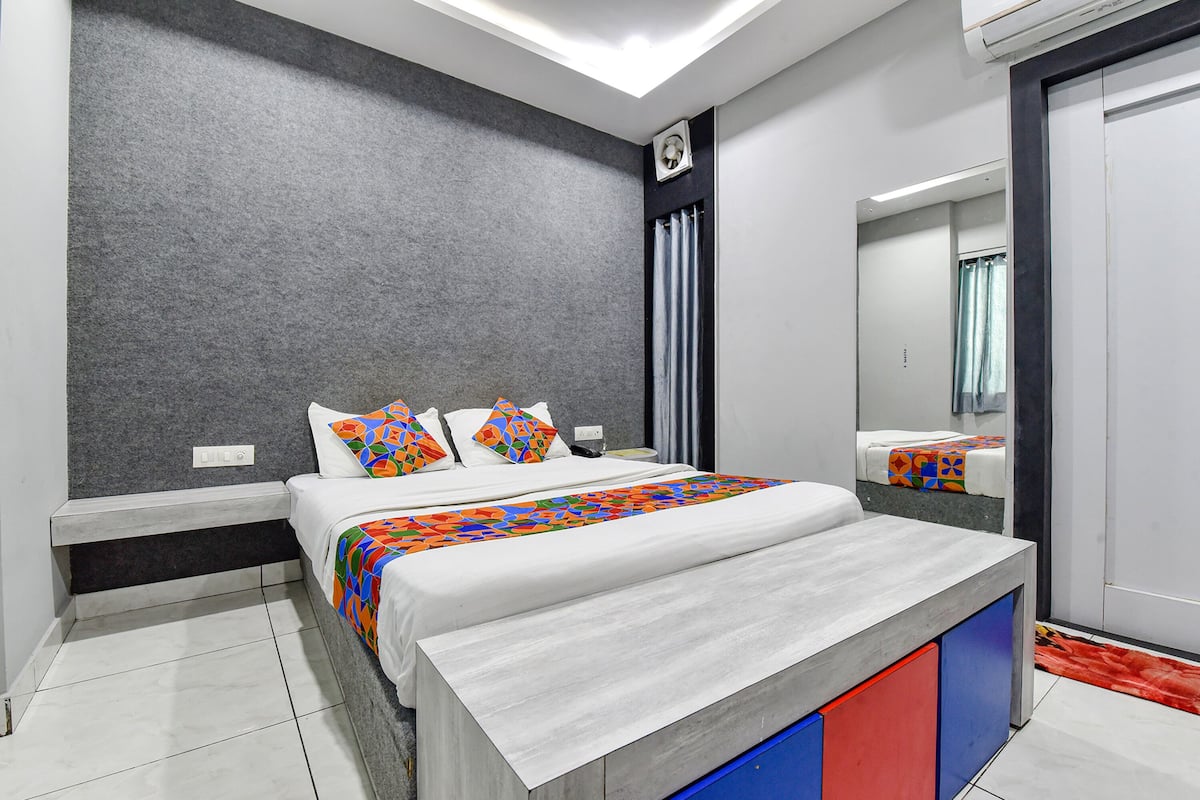 Une chambre moderne avec un grand lit, une table de chevet, un miroir et un mur gris à texture.
