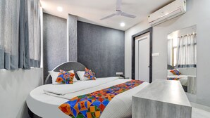 Une chambre d’hôtel moderne avec un grand lit, une table de chevet, un miroir et un ventilateur de plafond.