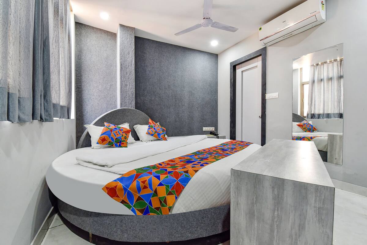 Une chambre d’hôtel moderne avec un grand lit, une table de chevet, un miroir et un ventilateur de plafond.