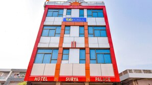 Un immeuble à plusieurs étages, sur lequel on peut voir une enseigne bien visible indiquant « Tab Hotels » et « Hotel Surya Palace ».
