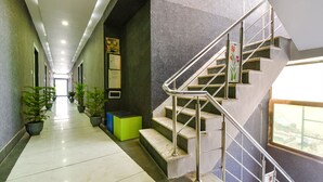 Un couloir avec un escalier, des plantes en pot et un espace détente agrémenté de verdure.