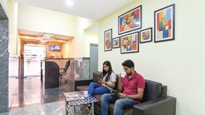A lobby with a reception desk, seating area, and artwork on the walls. - Fabhotel Olive Inn I (Barasat)