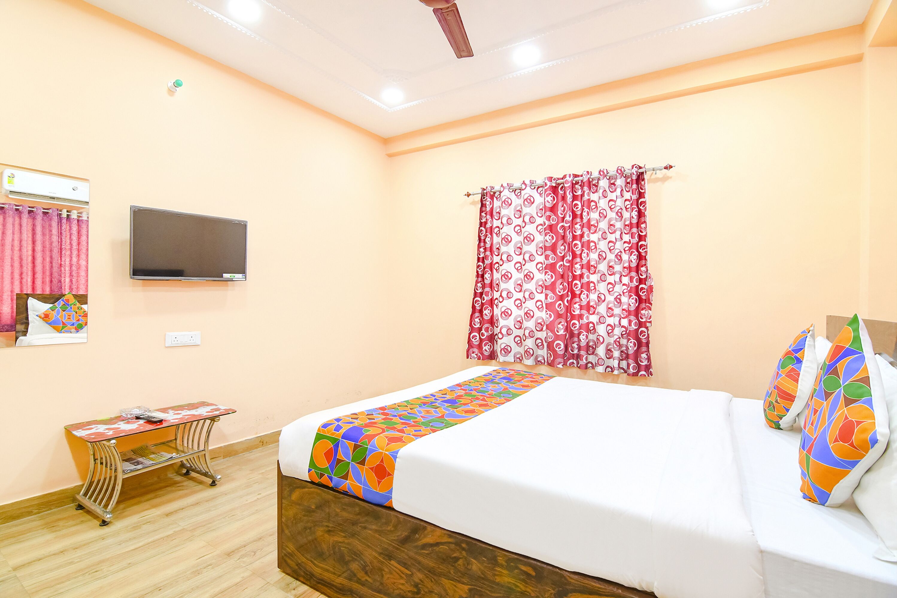Une chambre d’hôtel avec un lit, une télévision, un bureau et une fenêtre avec des rideaux.
