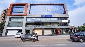A modern hotel building with a large glass facade, a sign for 'Niraant Hotel', and a 'fabHOTELS' sign. - Fabhotel Niraant (Surat)
