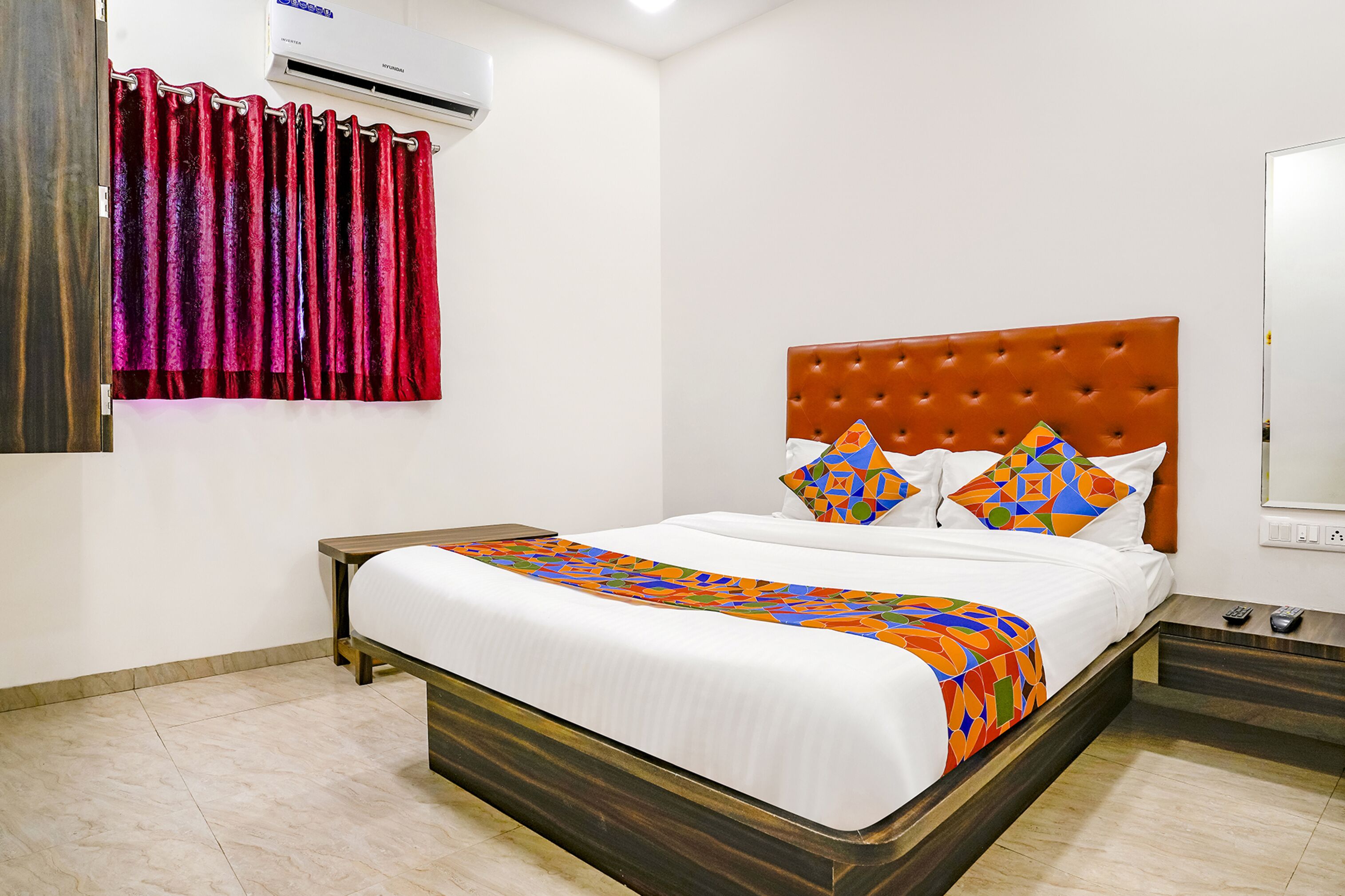 A neatly made bed with a patterned bedspread, a brown headboard, and decorative pillows.