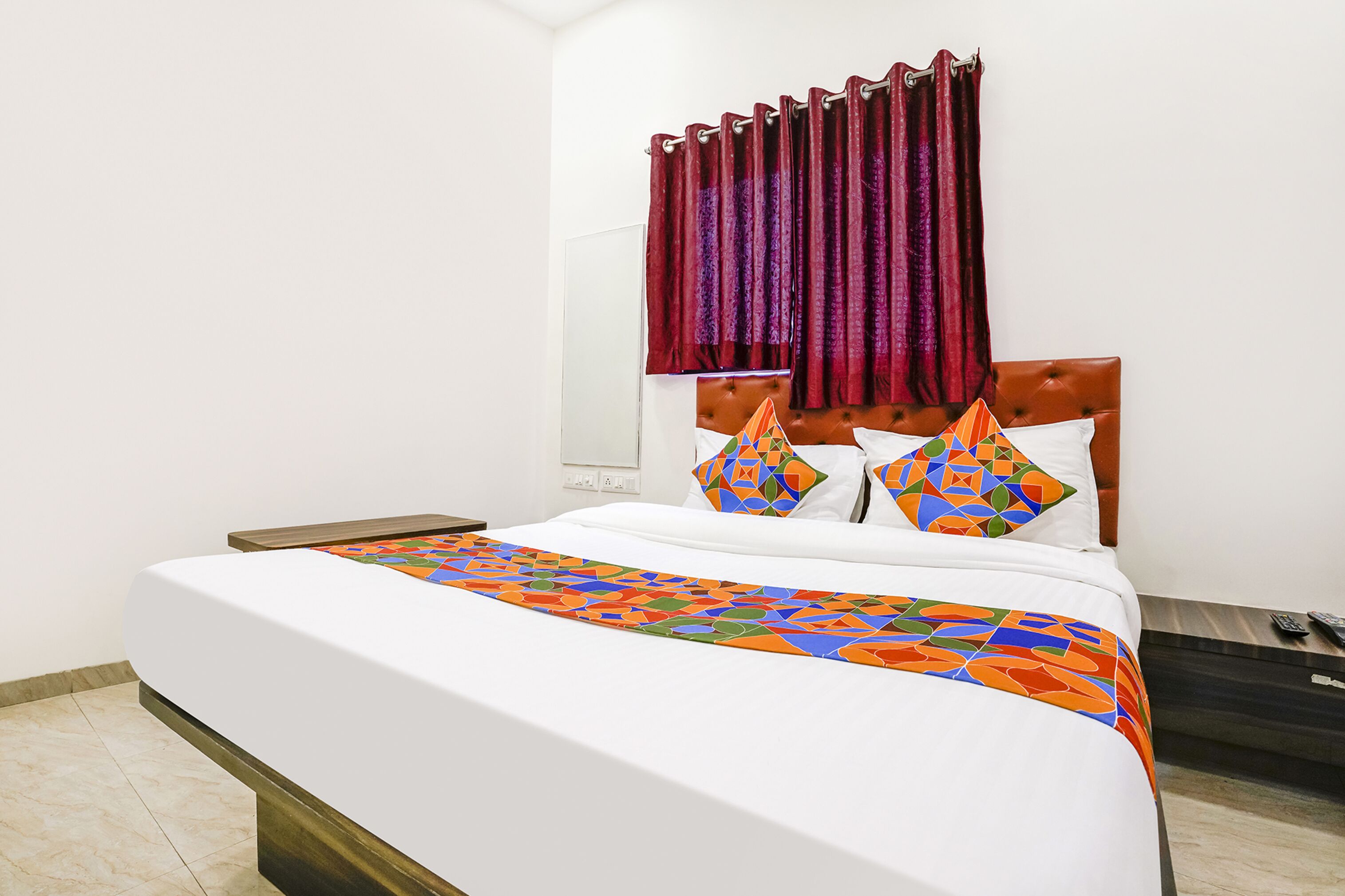 A neatly made bed with a colorful geometric-patterned bedspread and two decorative pillows.