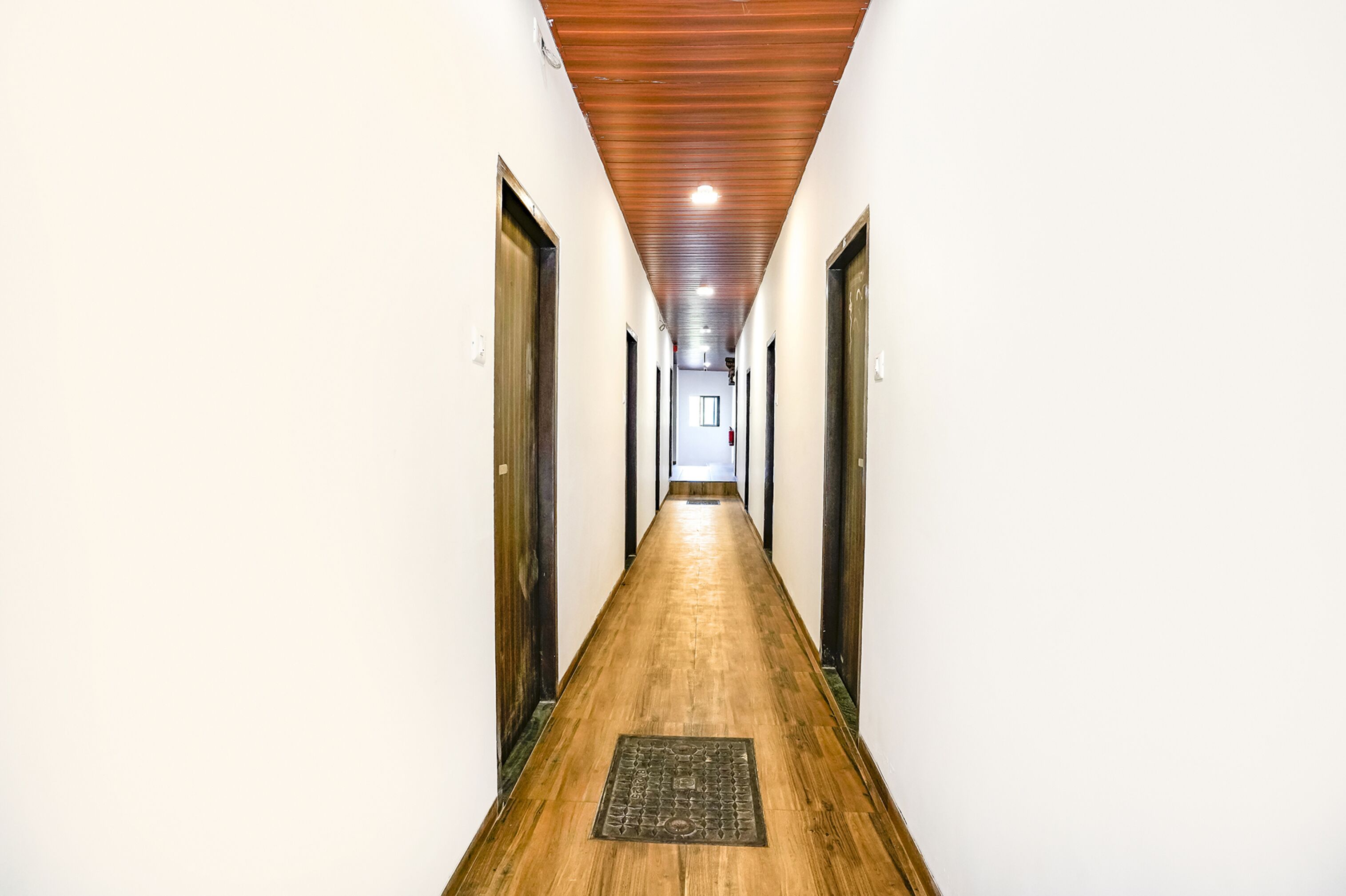 A long, narrow hallway with wooden flooring and white walls.