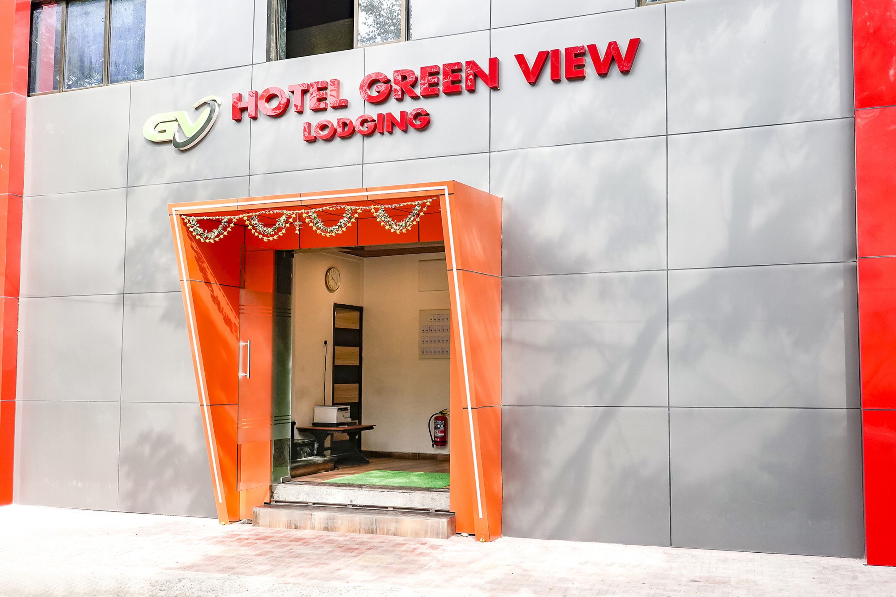The exterior of Hotel Green View, featuring a modern facade with a prominent entrance and a visible fire extinguisher on the wall.