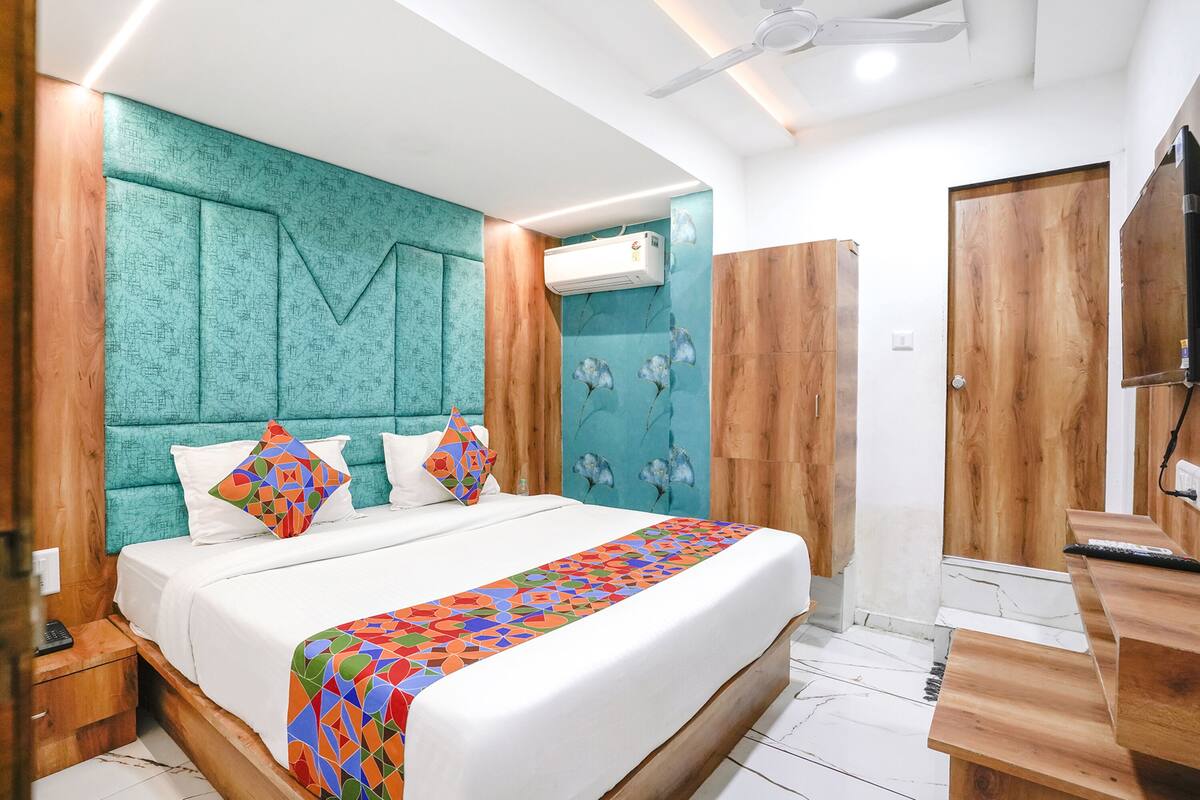 A modern bedroom with a large bed, wooden headboard, and a colorful geometric-patterned bedspread.