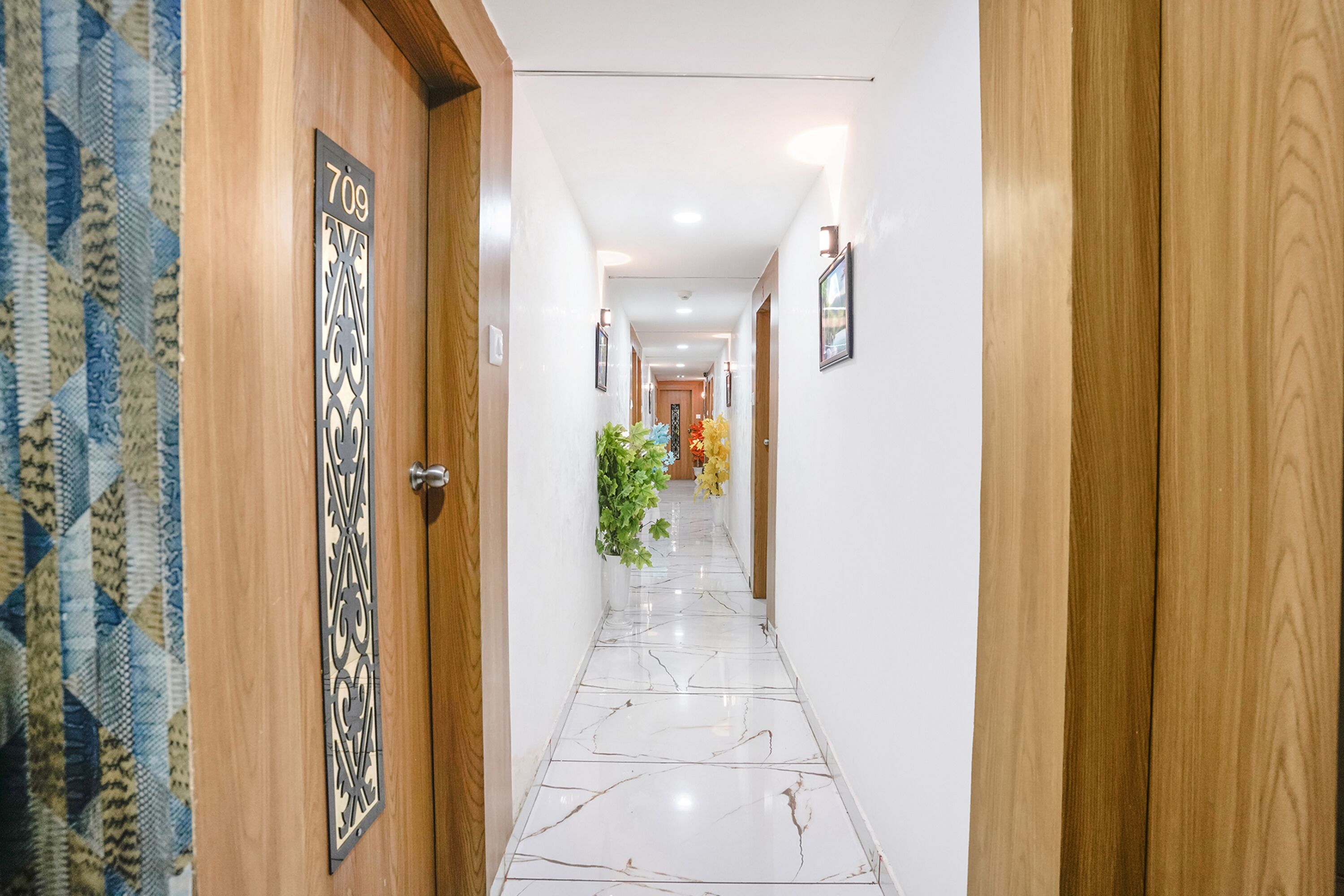 A hallway with a marble floor, wooden doors, and a number sign.