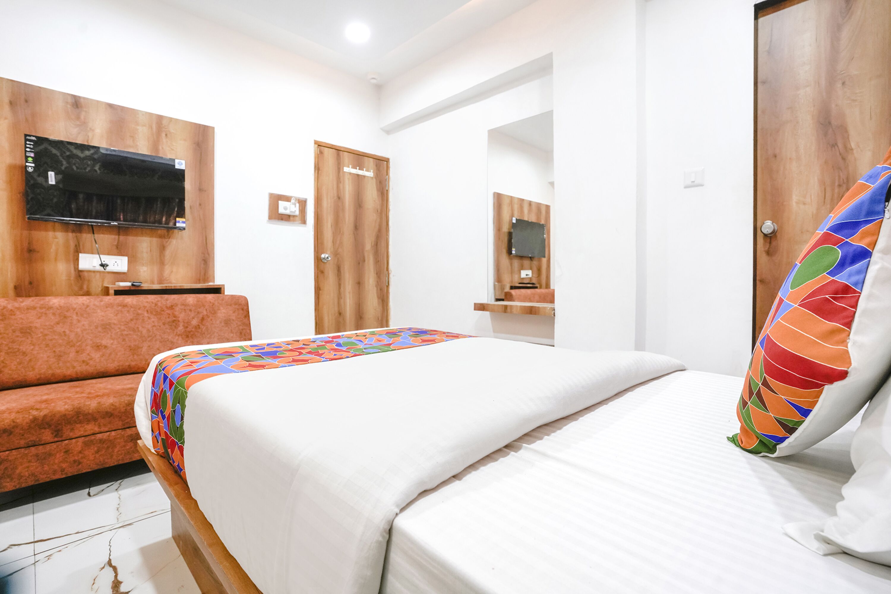 Una habitación de hotel con cama, sof á, televisor montado en la pared y puerta de madera.