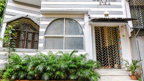 Un edificio con un amplio ventanal de arco, una entrada con rejas y fachada de baldosas.