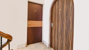 Una puerta de madera con una placa de número y un picaporte metálico.