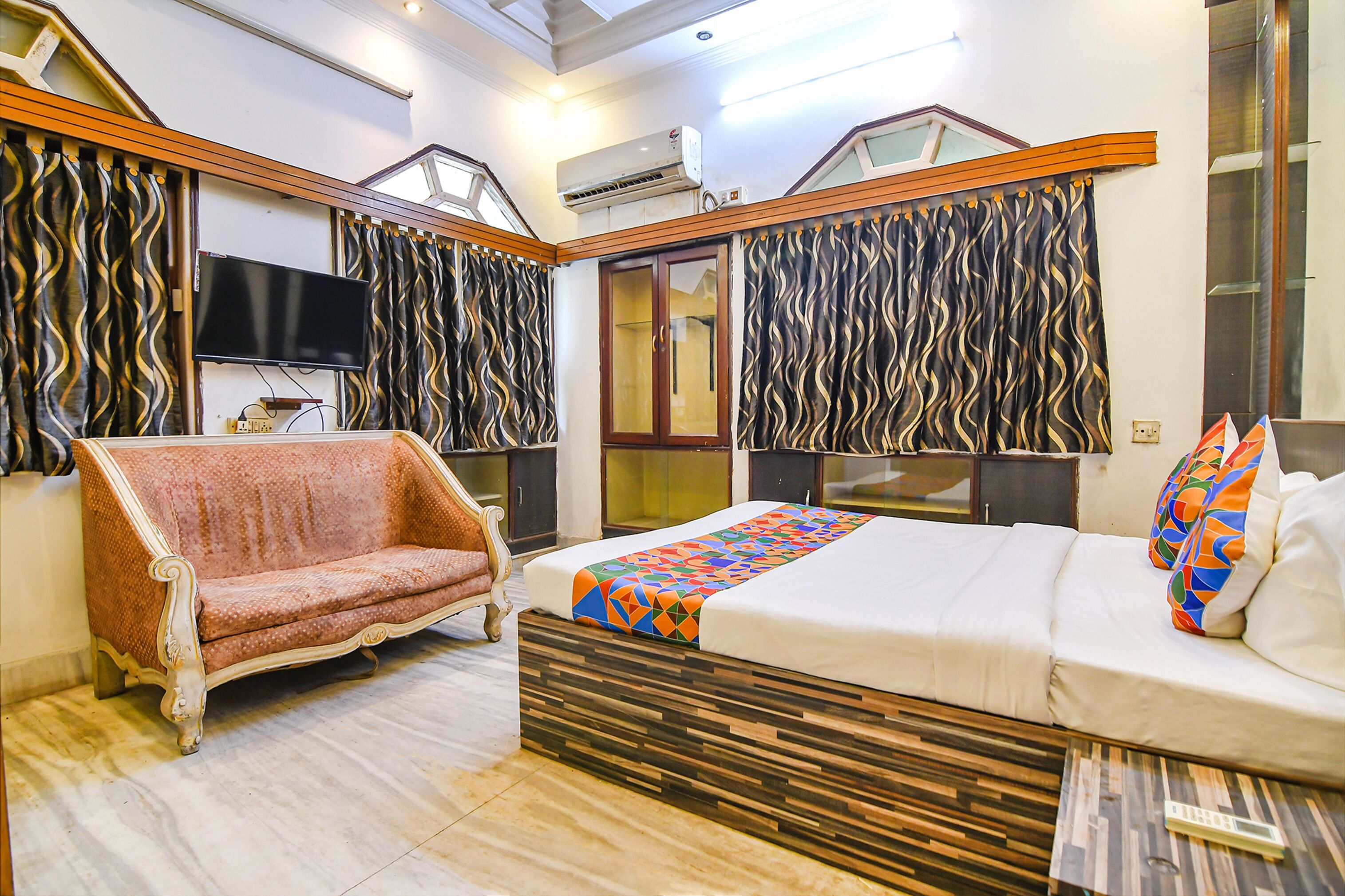 Une chambre moderne avec un lit, un canapé, une télévision et une fenêtre avec des rideaux.