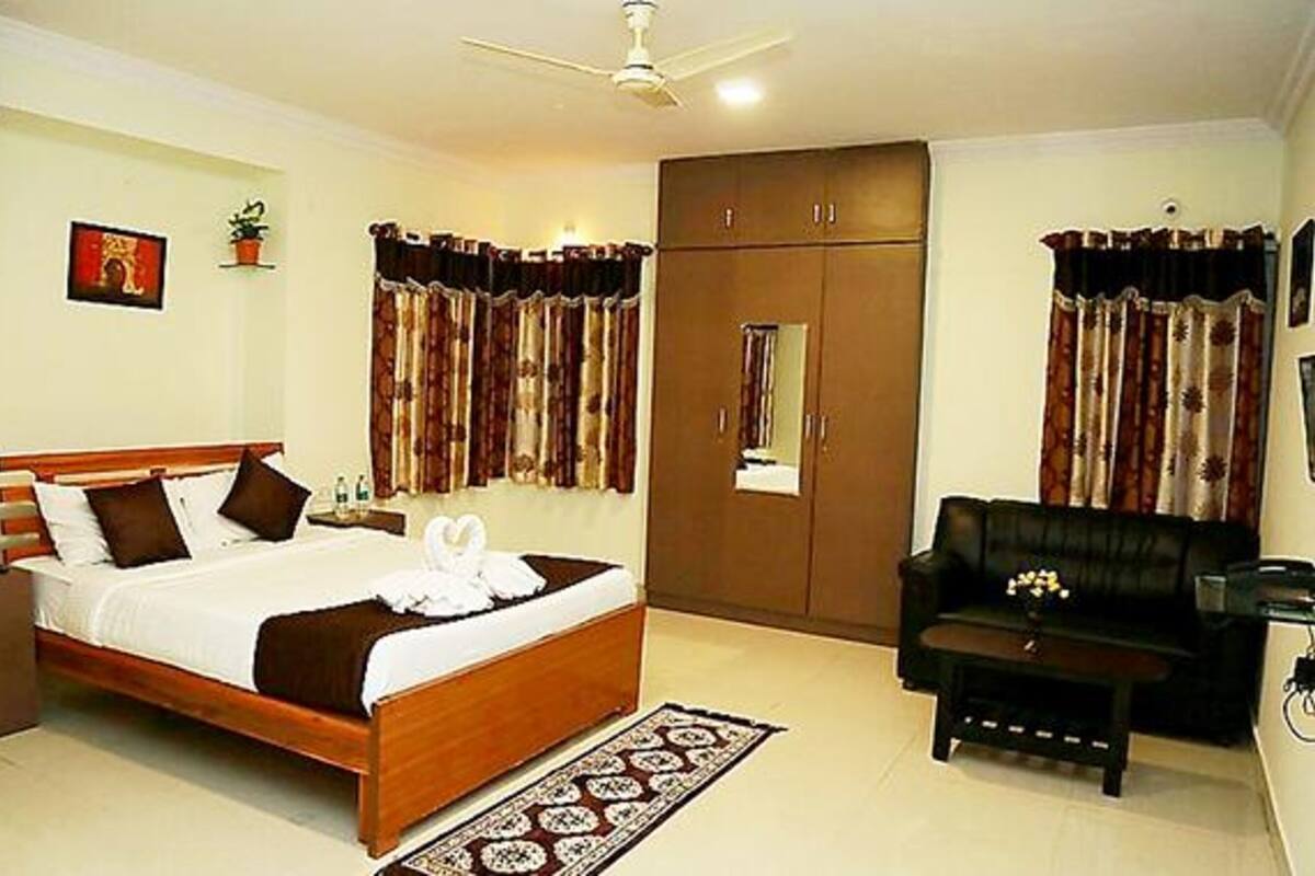 A hotel room with a bed, a wardrobe, a sofa, and a desk.