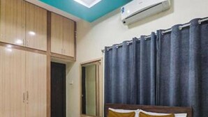 A bedroom with a bed, wooden wardrobe, and an air conditioning unit. - Fabexpress Bb Suites (Hyderabad)