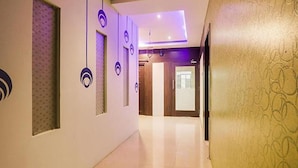 A hallway with a patterned wall, a door with a frosted glass panel, and a ceiling with recessed lighting. - Fabexpress Bb Suites (Hyderabad)