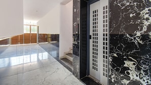 A modern interior with a marble staircase, a black and white marble wall, and a glass elevator. - FabHotel Prime Esta Inn - Nr. Novotel Pune Nagar Road, Viman Nagar (Pune)