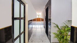 A hallway with a marble floor, a plant, and a door leading to a room. - FabHotel Prime Esta Inn - Nr. Novotel Pune Nagar Road, Viman Nagar (Pune)