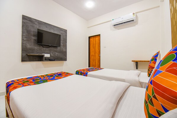 A hotel room with two beds, a flat-screen TV mounted on the wall, and an air conditioning unit.
