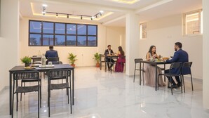 A modern dining area with a city view, multiple tables, and chairs. - FabHotel Prime Esta Inn - Nr. Novotel Pune Nagar Road, Viman Nagar (Pune)