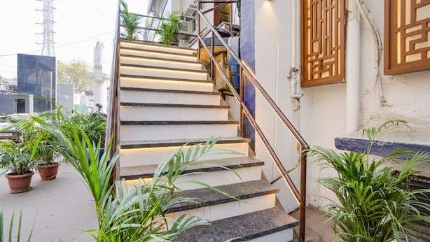A staircase with a metal railing leading to a building entrance, surrounded by potted plants. - FabHotel Prime Esta Inn - Nr. Novotel Pune Nagar Road, Viman Nagar (Pune)