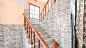 Un escalier avec des balustrades en bois et des panneaux muraux qui imitent la pierre.