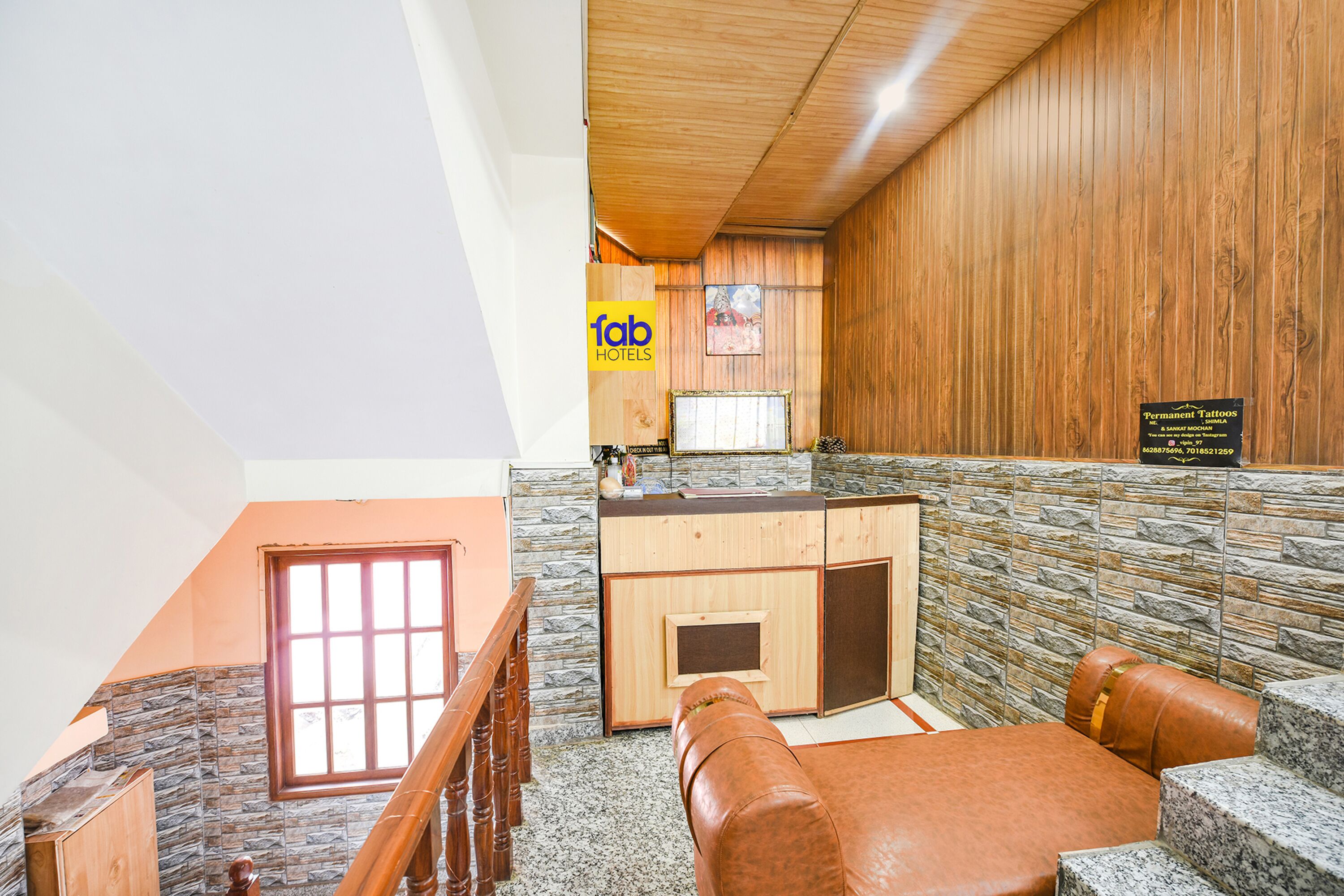 A hotel lobby with a stone wall, wooden paneling, a reception desk, and a seating area.