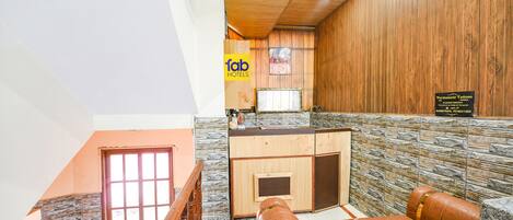 A hotel lobby with a stone wall, wooden paneling, a reception desk, and a seating area.