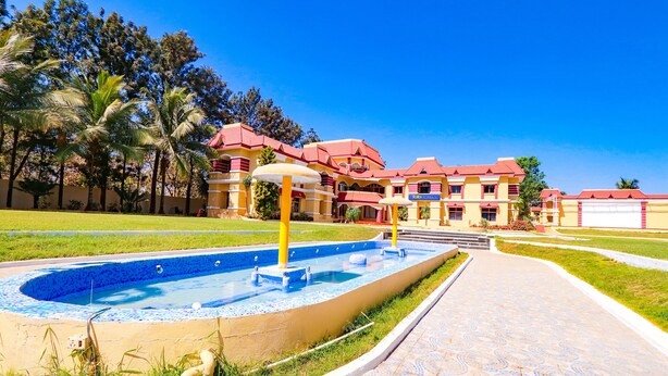 Piscina con una fuente, rodeada por un paseo y palmeras.