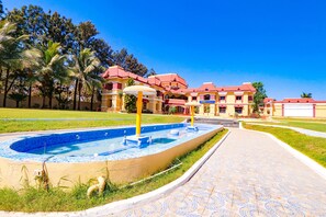 Piscina con una fuente, rodeada por un paseo y palmeras.