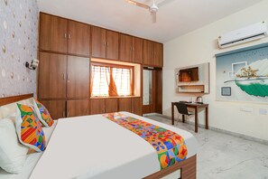 A bedroom with a bed, wooden wardrobe, desk, chair, and an air conditioning unit. - Fabhotel Lavish Palms (Hyderabad)