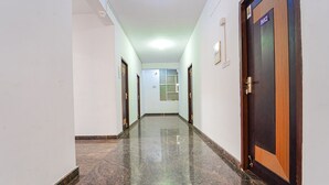 Un pasillo con piso pulido, una puerta con el símbolo de número y una ventana al final.