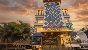 A hotel with a modern design, featuring a prominent tower structure and a sign indicating it is a FabHotels property. - Fabhotel Prime Suloka Towers (Kushalnagar)