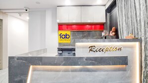 Ein Hotel-Rezeptionsbereich mit Marmor-Theke, einem Empfangstresen mit der Beschriftung „Reception“ und einem Schild für „Fab Hotels.“