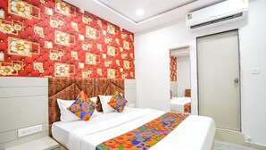 Ein Hotelzimmer mit einem großen Bett, einer Wand mit rotem Muster, einem braunen Kopfteil und einem weißen Nachttisch.