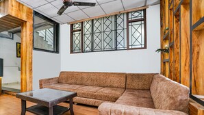 Una sala de estar moderna con un sofá seccional marrón, una mesa de centro de vidrio y un ventilador de techo.