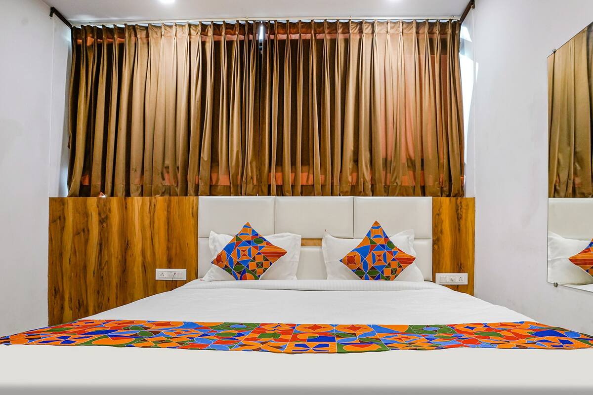 A bed with a white headboard, a colorful geometric-patterned bedspread, and two decorative pillows.