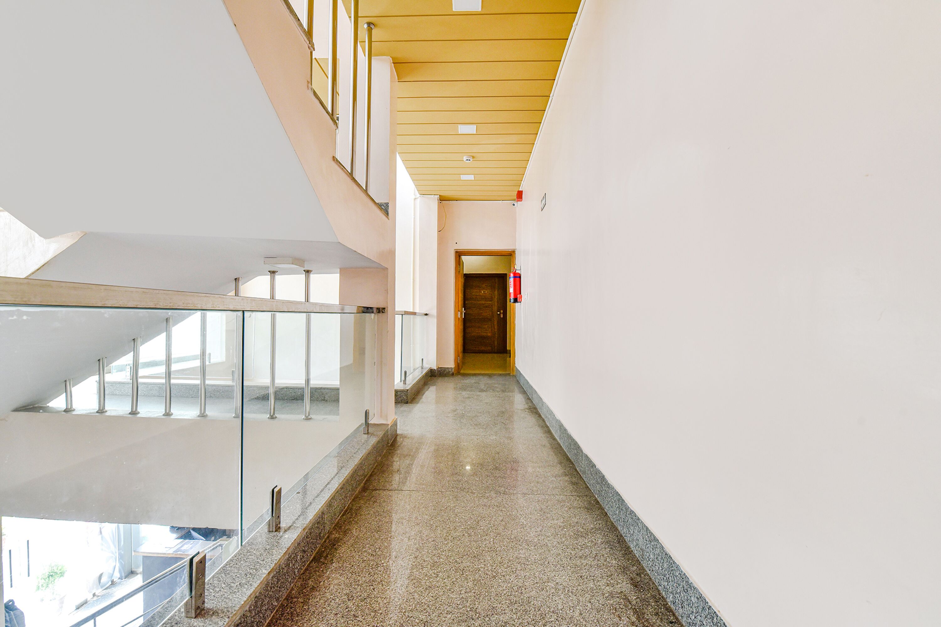 Un intérieur moderne avec une balustrade en verre, un sol en pierre polie et un plafond en bois.