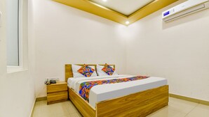 Une chambre à coucher avec un lit en bois, une table de chevet, une commode et un climatiseur fixé au mur.