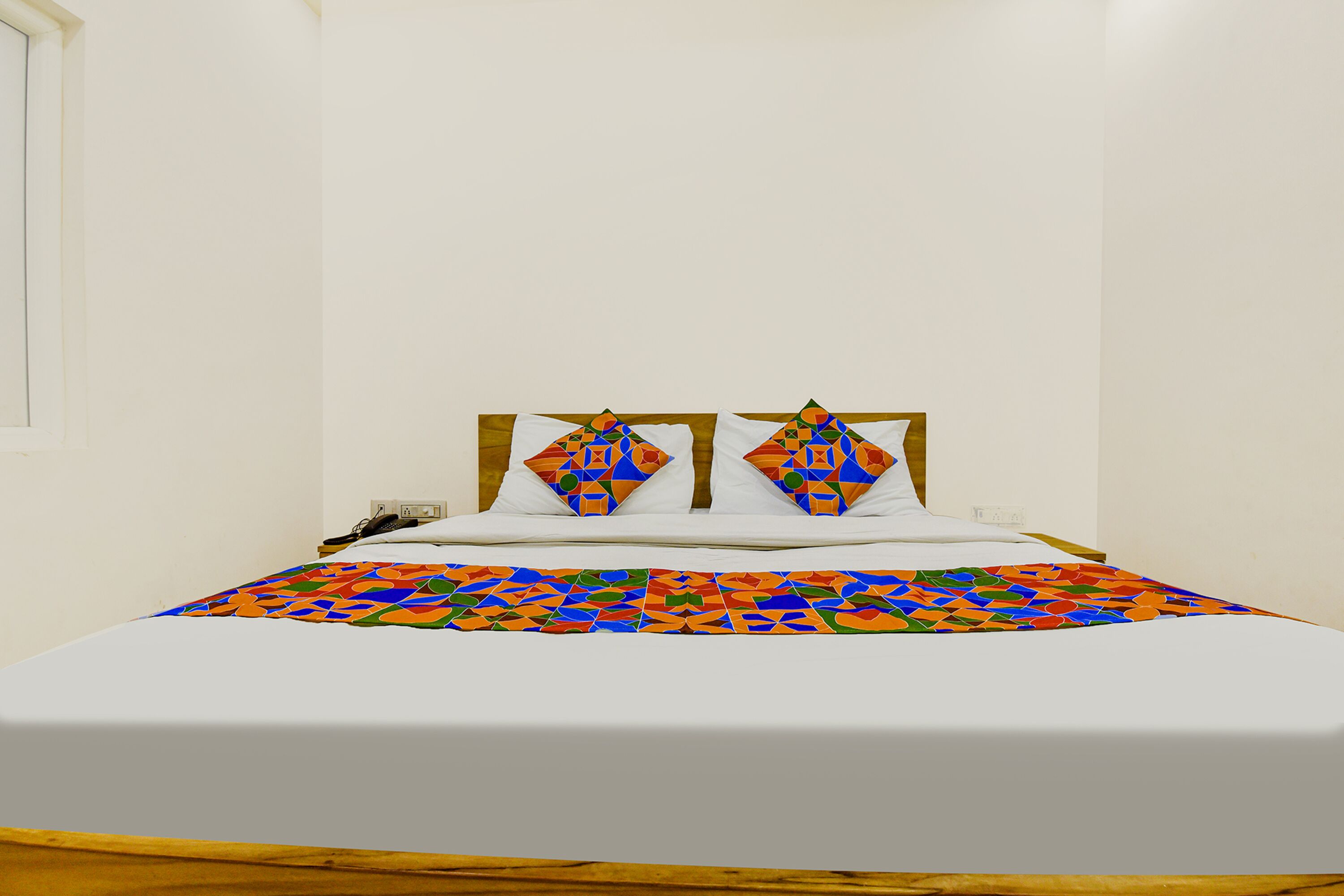 A bed with a colorful geometric-patterned bedspread and two pillows with a similar design.