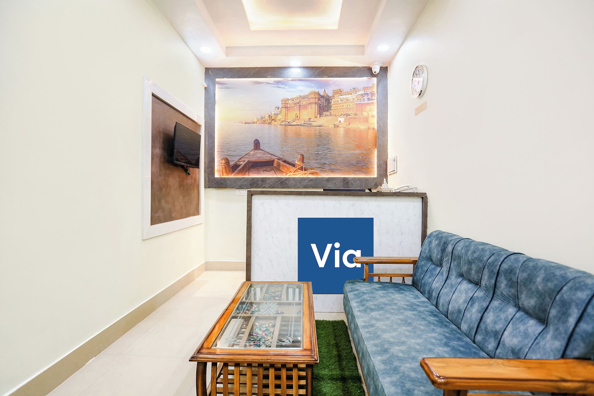 A living room with a sofa, a coffee table, a TV, and a wall-mounted painting.