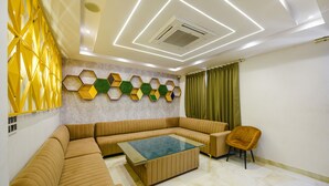Una sala de estar moderna con un sofá seccional, una mesa de centro de vidrio y una pared decorativa con patrones hexagonales.