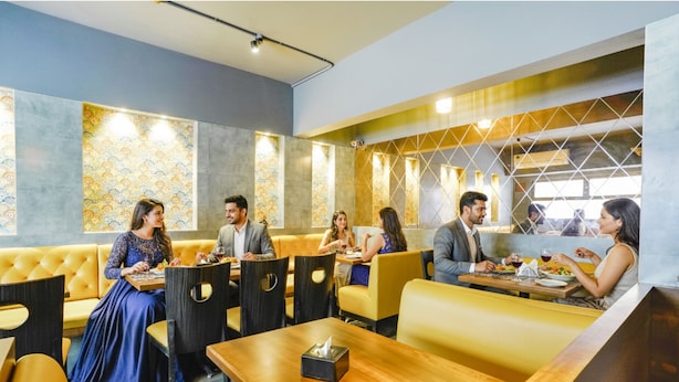 A restaurant with booths and tables, featuring patterned wall decor and a geometric design on the back wall. - FabHotel Kuber (Navi Mumbai)